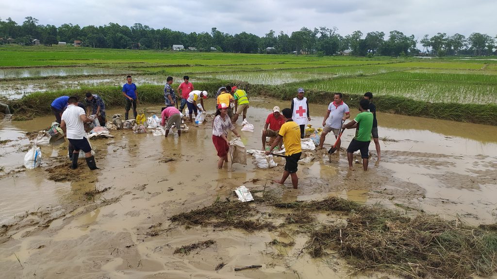 Nepal Red Cross Society volunteers and local people strengthen a breached embankment to prevent floodwater from entering their settlement. Photo by  Nepal Red Cross Society