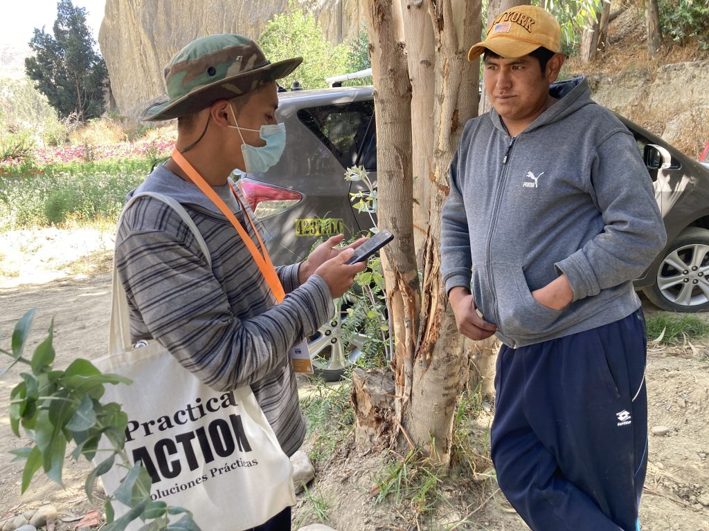 Young field worker interviewing community member for Flood Resilience Measurement for Communities (FRMC) data collection in Mecapaca, Bolivia.